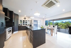 Una cocina moderna con una isla central, muebles oscuros y un comedor con vistas.