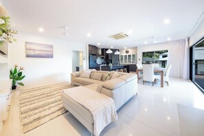 A modern living room with a sofa, ottoman, and dining area. - Jubilee Sanctuary (Jubilee Pocket)