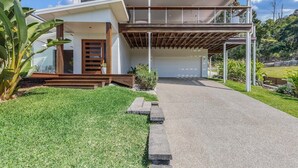 Una casa moderna de dos pisos con un garaje techado, un patio delantero cuidado y un jardín bien mantenido.