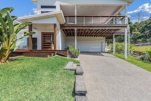 Ein modernes, zweistöckiges Haus mit überdachter Auffahrt, Garage und gepflegtem Rasen.