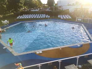 Une piscine dotée de plusieurs couloirs, d’un poste de surveillance pour les sauveteurs et d’un espace aménagé avec des chaises longues.