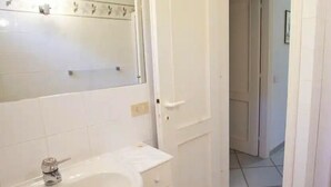 Casa de banho com uma sanita branca, espelho e porta.