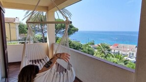 Una persona si rilassa in un'amaca su un balcone con vista sul mare.