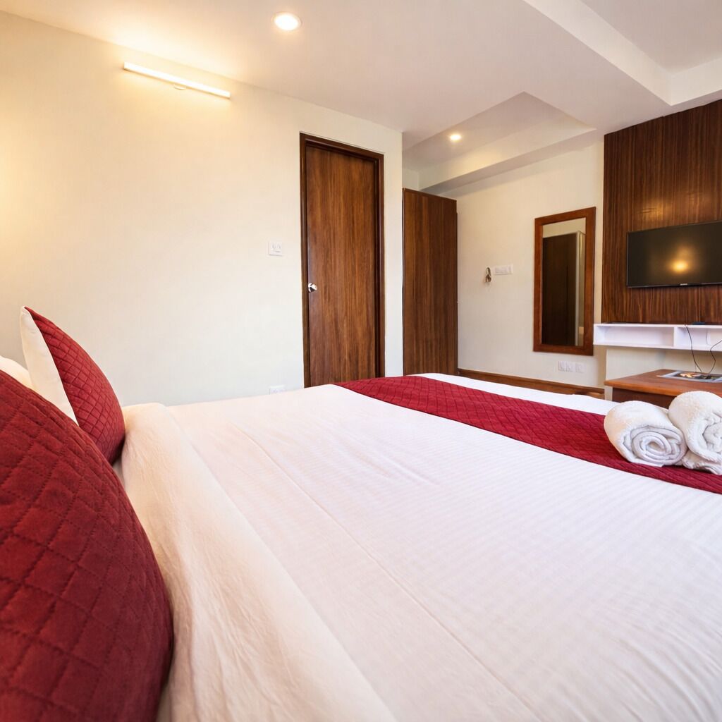 A hotel room with two beds, a TV, and a mirror.