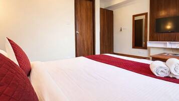 A hotel room with two beds, a TV, and a mirror.