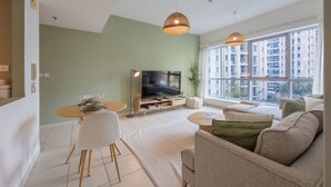 A modern living room with a sofa set, a dining table, and a TV. - The Point Tower - Vibrant One Bed in Marina (Dubai Marina)