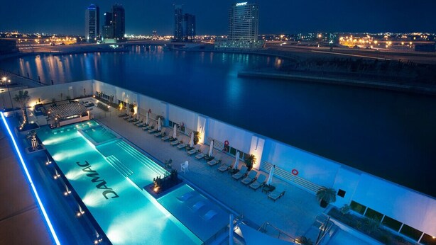 Zona de piscina con sillones de descanso y vistas al horizonte urbano nocturno.