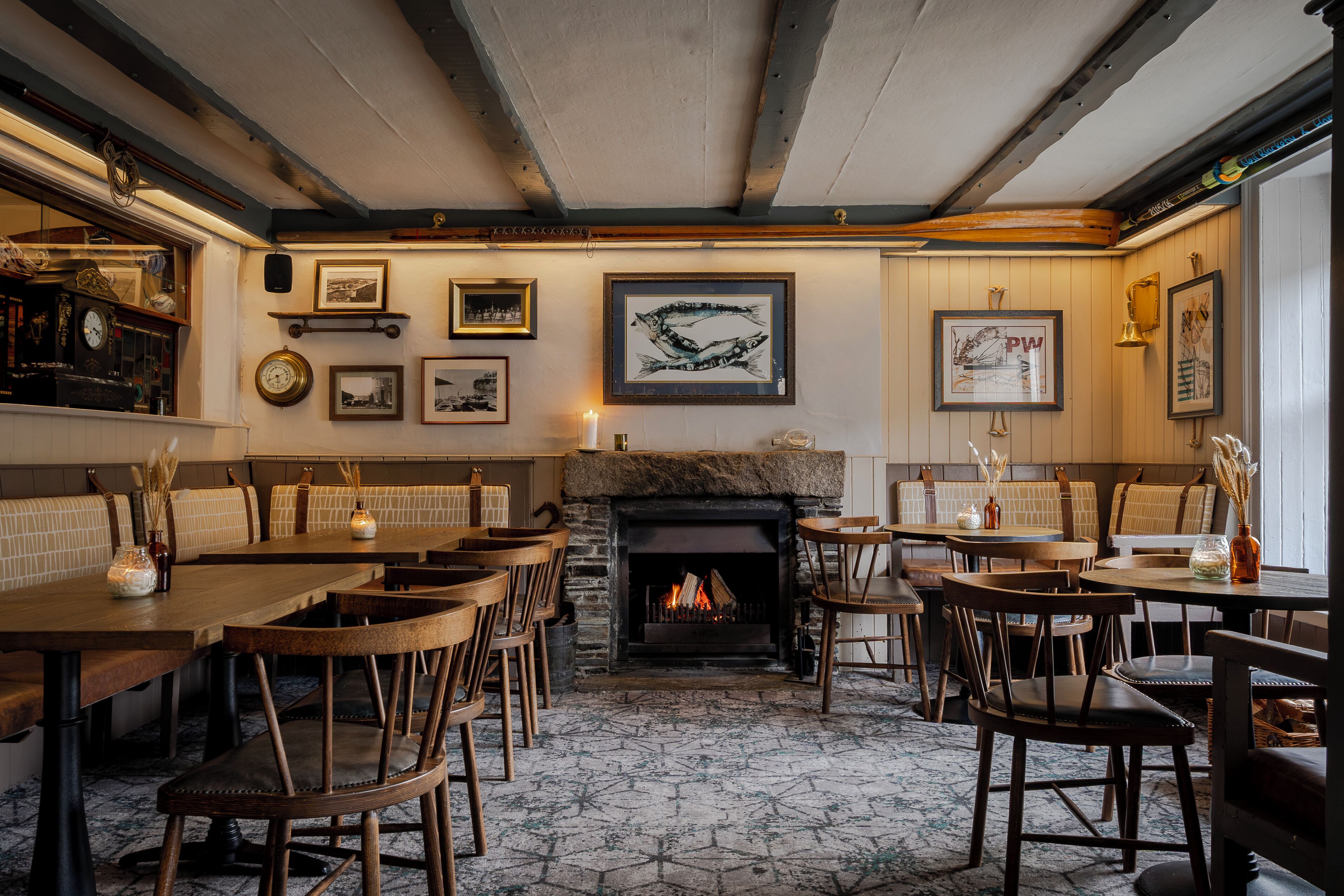 A cozy restaurant with wooden furniture, a fireplace, and various framed pictures on the walls.