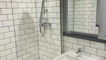 Een moderne badkamer met witte metrotegels, een glazen douchecabine, een wastafel met spiegel en een handdoekrek.