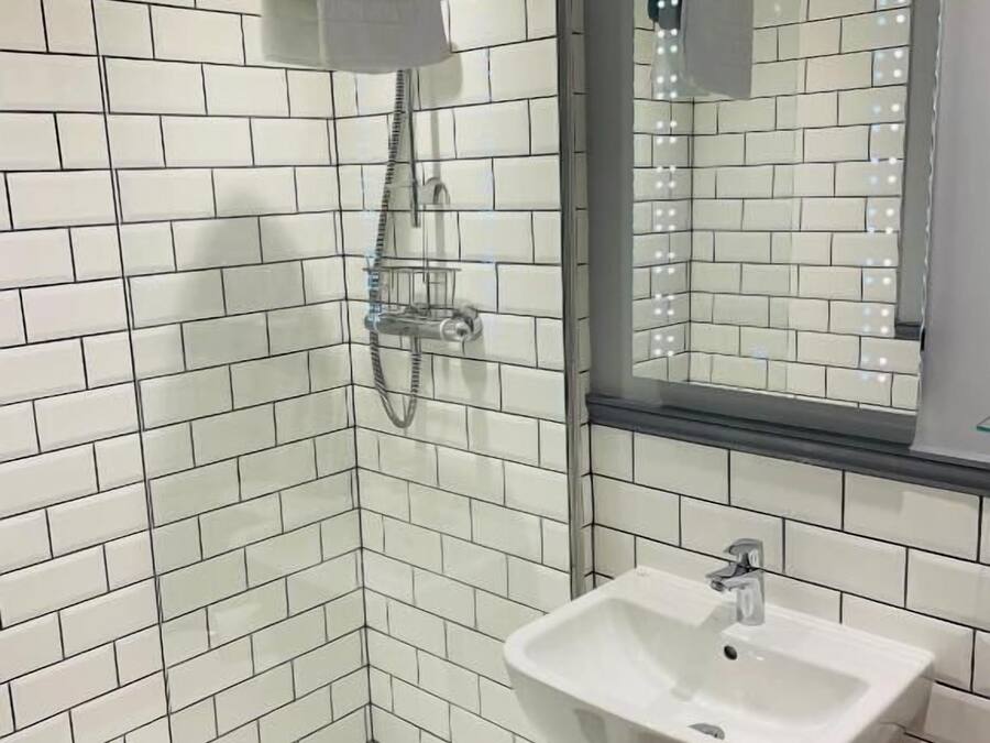 Een moderne badkamer met witte metrotegels, een glazen douchecabine, een wastafel met spiegel en een handdoekrek.