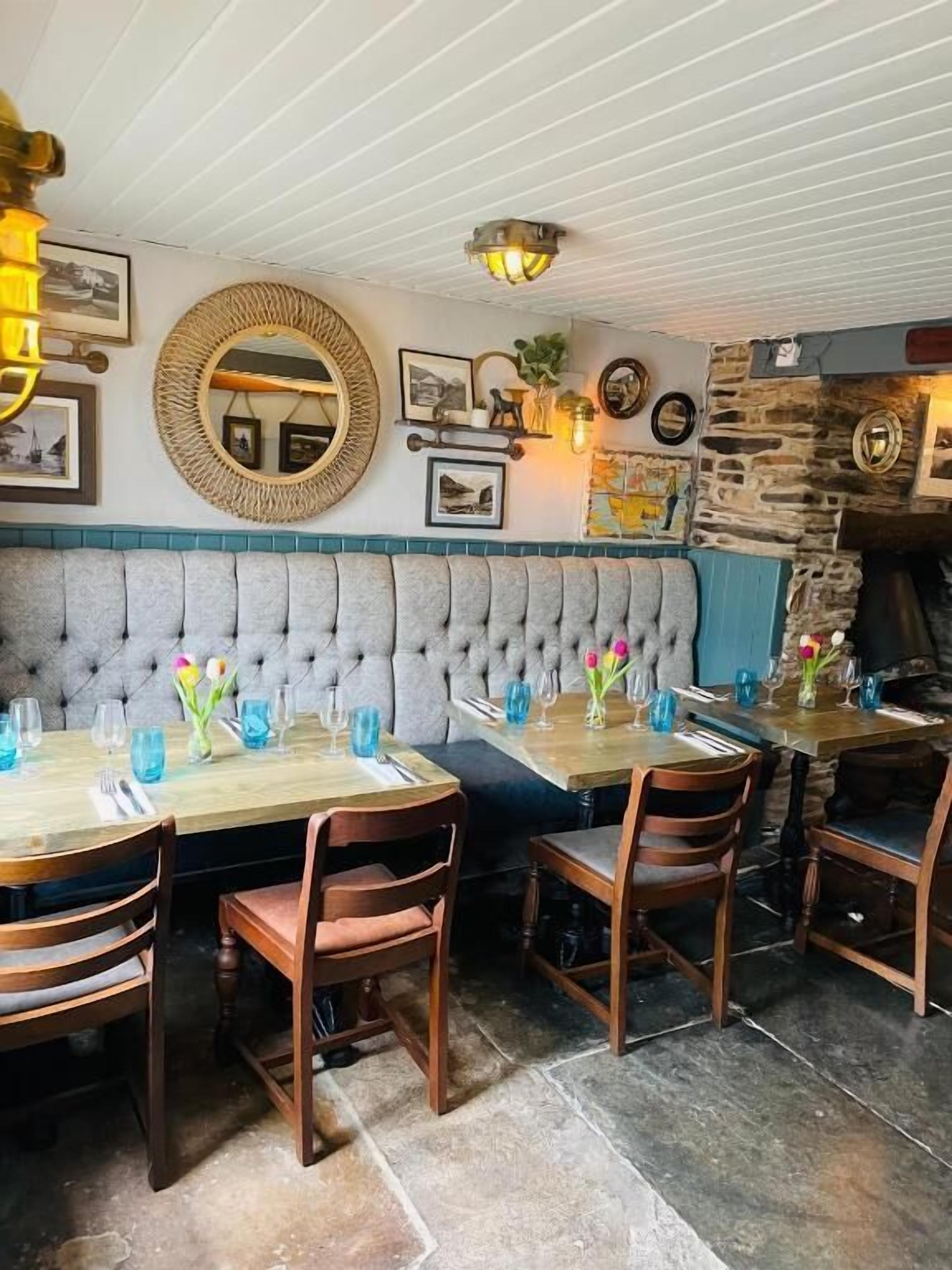 Ein Restaurant mit gepolsterten Sitzbänken, Holztischen und Stühlen.