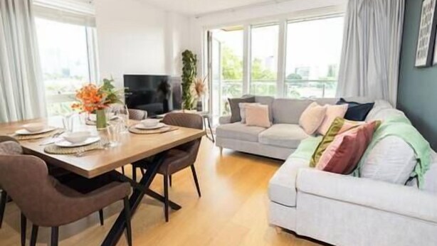 Una sala de estar moderna con comedor, un sofá gris y un televisor de pantalla plana.