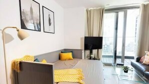 Una habitación de hotel moderna con cama, escritorio, silla, televisor de pantalla plana y balcón con vistas a la ciudad.