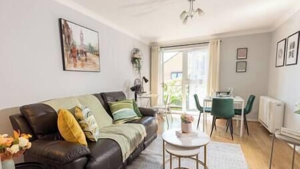 A modern living room with a leather sofa, a round coffee table, and a dining area with a table and chairs.