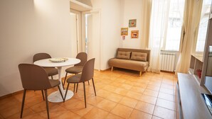 A dining area with a round table and four chairs, a sofa, and a television. - Historic center of Rome, 2 steps from the Colosseum (Roma)