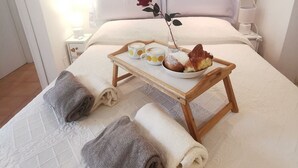 A neatly made bed with a tray of breakfast items, including pastries and a rose. - Historic center of Rome, 2 steps from the Colosseum (Roma)