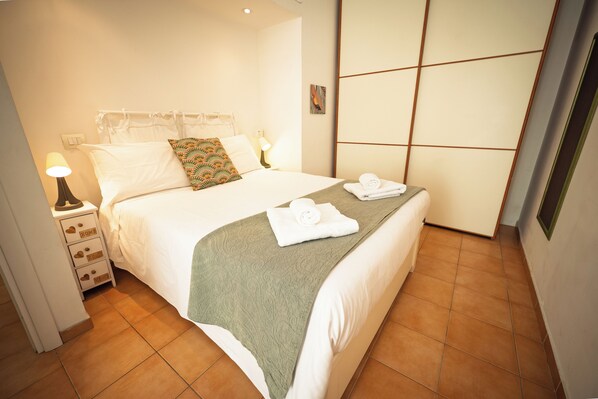 A neatly made bed with a green blanket, white pillows, and a rolled towel on the side. - Historic center of Rome, 2 steps from the Colosseum (Roma)
