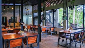 An indoor dining area with wooden tables and chairs, large windows, and hanging pendant lights. - Penginapan Alam DGlorious CraterKamojang (Mekarwangi)