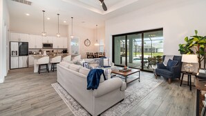 Amplia sala de estar con un sofá grande, una mesa de centro y un comedor con una cocina al fondo.