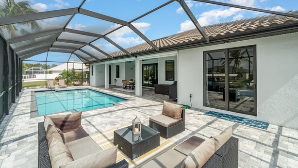 Un espacio al aire libre cubierto con piscina, mobiliario exterior y un patio con suelo de baldosas.