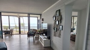 Un vaste espace de vie avec un balcon donnant sur la mer, une table à manger et un coin salon confortable.
