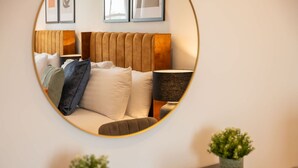 A bedroom with a round mirror reflecting the bed, pillows, and bedside lamp. - Host Stay Princes Place Hideaway IV (Liverpool)