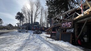 Un carrer nevado amb un restaurant de pizza i un cartell de cotxes de lloguer.