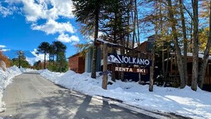 Un camí cobert de neu que condueix a un edifici amb un rètol que diu 'Volcano Renta Ski'.