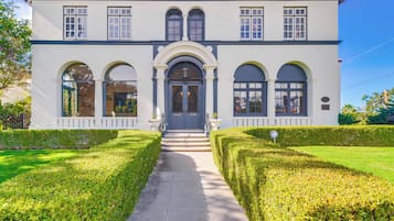 A two-story building with a symmetrical facade, large windows, and a central entrance with steps.
