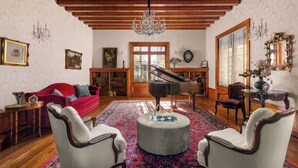 A spacious living room with a grand piano, red sofa, and elegant furniture.