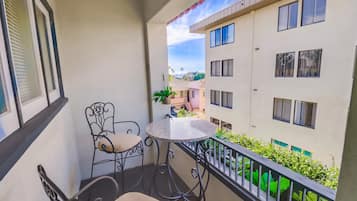 A balcony with a round table and two chairs, overlooking a residential area with multiple buildings.