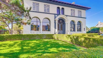 A two-story building with a white facade, arched windows, and a red-tiled roof.