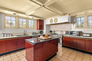 Une cuisine spacieuse dotée d’un îlot central, de grandes fenêtres et d’appareils électroménagers modernes.