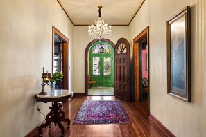 Un couloir orné d’un lustre, avec une porte verte et un tapis à motifs.