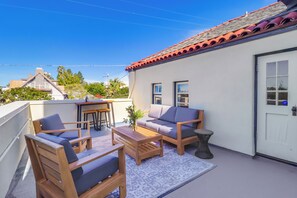 A rooftop patio with wooden furniture, a small table, and a potted plant. - The Coulter House by Gather: Historic San Diego Estate w/ Ocean Views (San Diego)
