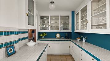 A kitchen with white cabinets, a blue accent wall, and a tiled backsplash.
