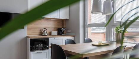 Una cocina moderna con armarios blancos, encimera de madera y comedor con mesa y sillas.