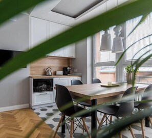 Una cocina moderna con armarios blancos, encimera de madera y comedor con mesa y sillas.