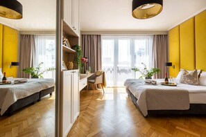 A hotel room with two beds, a desk, a chair, and a large window with curtains.