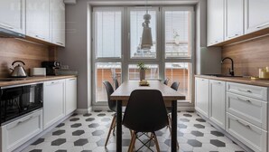 A modern kitchen with white cabinets, a black dining table, and a hexagonal tile floor. - Feniks Stunning 2-bed apartment with 3 terraces (Kraków - Feniks)