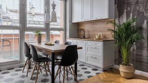 Een moderne keuken met witte kasten, een houten aanrecht en een eethoek met een tafel en stoelen.