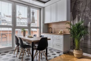 Een moderne keuken met witte kasten, een houten aanrecht en een eethoek met een tafel en stoelen.