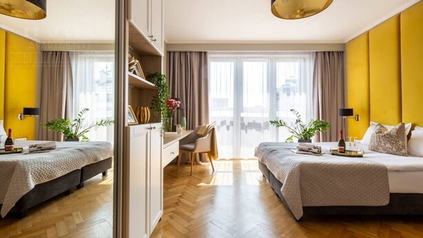 Een hotelkamer met twee bedden, een bureau, een stoel en een groot raam met gordijnen.