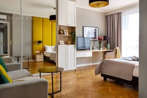 Una habitación de hotel moderna con una cama, un escritorio con televisor, un sofá y una mesita.