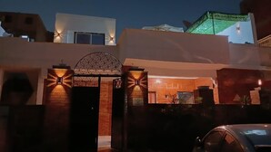 A modern building with a gated entrance, a brick wall, and a small garden area. - Pyramids Third Eye (Giza)