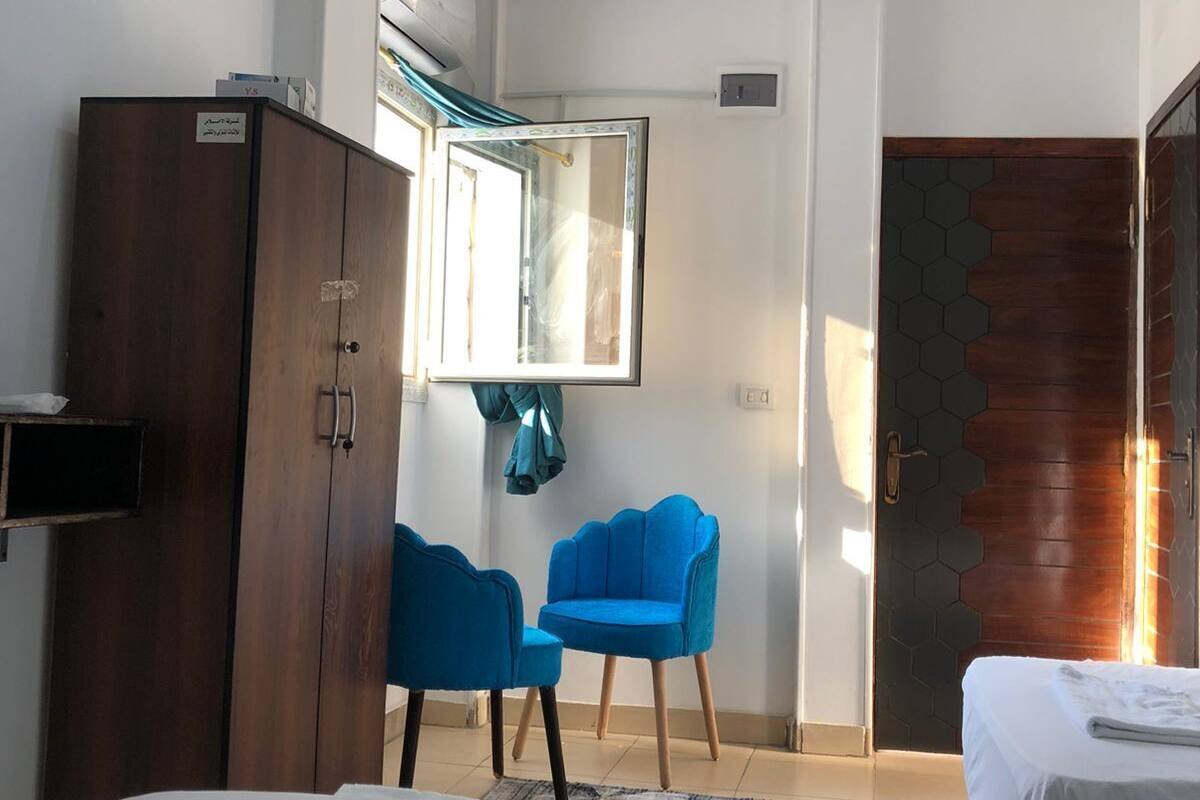 Ein Hotelzimmer mit einem Bett, einem Kleiderschrank, einem Schreibtisch mit Stuhl und einer Tür mit einem unverwechselbaren sechseckigen Muster.