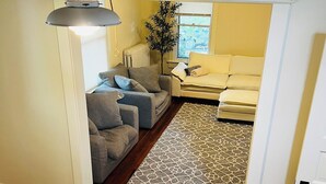 Un salón acogedor con un sofá gris, un sofá beige y una alfombra estampada.