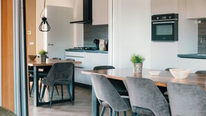Une cuisine moderne avec une table à manger en bois, des chaises à revêtement gris et un four encastré.