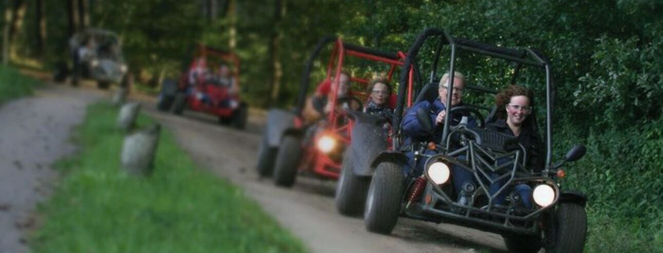 Een groep mensen in terreinwagens op een bosweg.