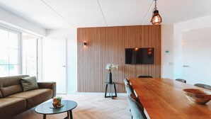 A modern living room with a wooden dining table, a sofa, and a small coffee table.